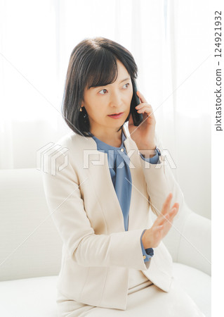 一位中年職業婦女用手勢與電話另一端的人交談 一位中年職業婦女用手勢與電話另一端的人交談 124921932