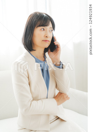 A middle-aged career woman using gestures to talk to the person on the other end of the phone 124921934