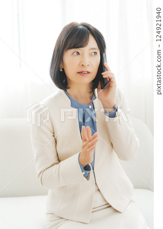 A middle-aged career woman using gestures to talk to the person on the other end of the phone 124921940