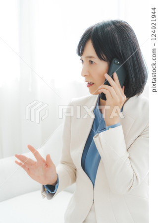 一位中年職業婦女用手勢與電話另一端的人交談 124921944