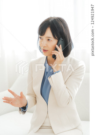 一位中年職業婦女用手勢與電話另一端的人交談 一位中年職業婦女用手勢與電話另一端的人交談 124921947