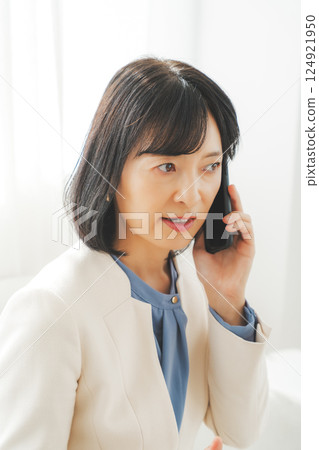 一位中年職業婦女用手勢與電話另一端的人交談 一位中年職業婦女用手勢與電話另一端的人交談 124921950