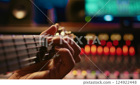 Musician singer recording a new song on his electro acoustic guitar, creating new music in professional studio control room. Artist doing live performance with instrument. Close up. Camera B. 124922448
