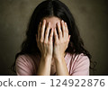 A young woman covers her face with her hands 124922876