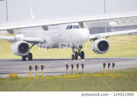 White passenger airplane taxiing on runway at airport 124922900