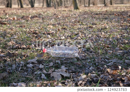 An empty plastic bottle on the ground in a city park. Environmental pollution. Environmental problem. City buildings side by side 124923783