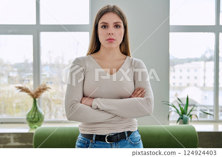 Portrait of confident young woman posing with crossed arms in home interior 124924403