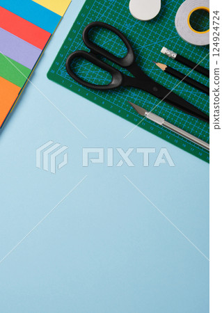 Supplies for paper art hobby: scissors, craft knife, pencil, eraser, colored paper. Space for your text. Paper crafts work table flatlay. 124924724
