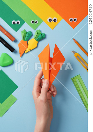 Making origami carrot. DIY project. Bend the corners of the triangle toward the center. Paper creativity. 124924730