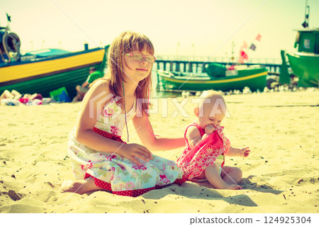 Toddler girl having fun with child on beach. 124925304