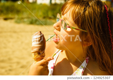 Toddler girl eating ice cream on beach 124925307