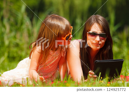 Mother and daughter with tablet pc in park Mother and daughter with tablet pc in park 124925772
