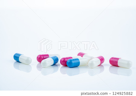 Blue and pink capsule pills spread on white background, showcasing pharmaceutical products, healthcare concepts, and the role of prescription medicine in advancing treatment and patient well-being. 124925882