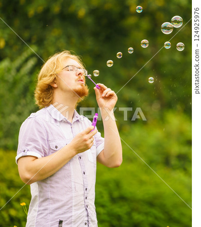 Man blowing soap bubbles outdoor 124925976