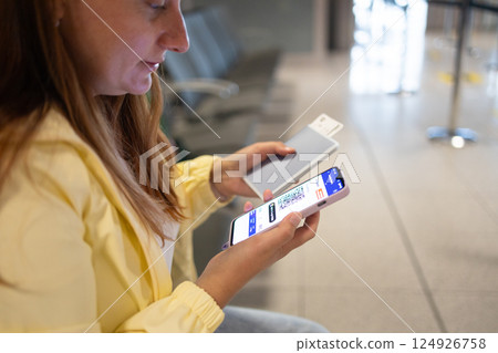 Young caucasian woman with suitcase, passport and ticket typing on smartphone, waiting for transport on train station or airport, cropped. Travel and device, app for trip, close up Young caucasian woman with suitcase, passport and ticket typing on smartphone, waiting for transport on train station or airport, cropped. Travel and device, app for trip, close up 124926758