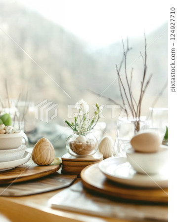 Modern Easter table setting by window with natural decor, flowers. Mountains are visible from window 124927710