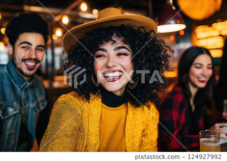 Young woman wearing a hat smiling with friends at a brewery 124927992