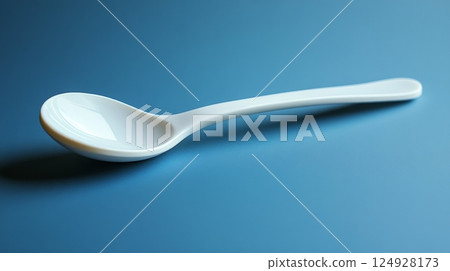 White ceramic spoon lying on a blue tablecloth 124928173