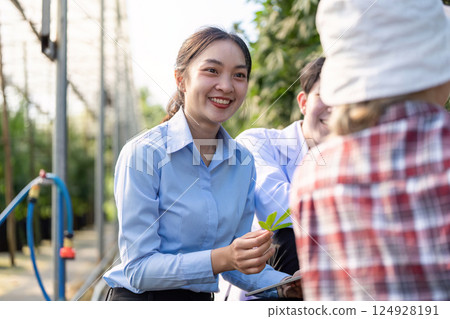 Friendly cannabis researcher engaging with a child while explaining plant characteristics in a greenhouse setting 124928191