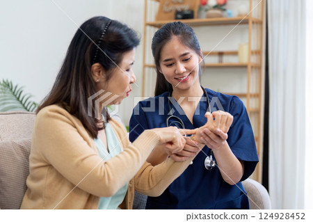 Caregiver checks symptoms of elderly patient with doctor and nurse in a cozy home environment 124928452