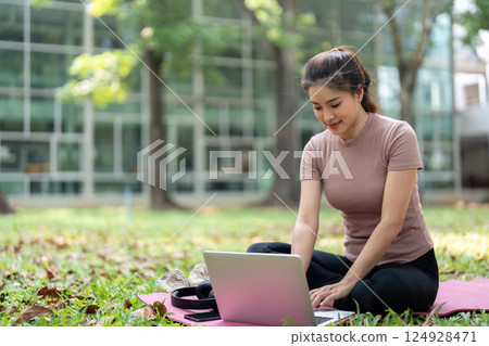 Wellness and Digital Productivity. A woman cheerfully typing on a laptop while maintaining her wellness routine outdoors. Wellness and Digital Productivity. A woman cheerfully typing on a laptop while maintaining her wellness routine outdoors. 124928471