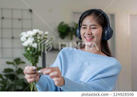 Joyful woman enjoying music with flowers at home lifestyle indoor setting cheerful mood 124928506