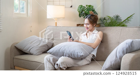 Relaxing woman using smartphone at home modern living room lifestyle cozy environment indoor scene 124928515