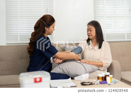 Wellness Check and Family Engagement. A caregiver measures vital stats while reassuring the patient at home. Wellness Check and Family Engagement. A caregiver measures vital stats while reassuring the patient at home. 124928548