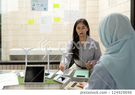 Sustainable Practices and ESG Strategies. A professional discussing sustainable energy solutions using models in a corporate meeting. Sustainable Practices and ESG Strategies. A professional discussing sustainable energy solutions using models in a corporate meeting. 124928698