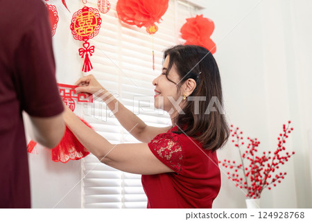 Elderly couple celebrating chinese new year at home festive decorations intimate indoor setting joyful atmosphere 124928768