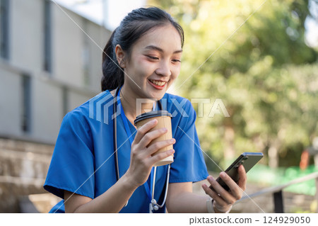 Asian Female Healthcare Worker Relaxing Outdoors with Coffee Asian Female Healthcare Worker Relaxing Outdoors with Coffee 124929050