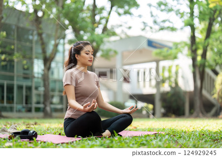 Wellness and Meditation. A woman practicing meditation outdoors with a serene expression, enhancing her mental well-being. 124929245
