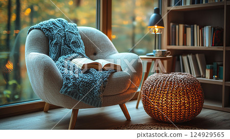 An inviting reading nook with a cozy armchair, a blanket, and an open book by the window. An inviting reading nook with a cozy armchair, a blanket, and an open book by the window. 124929565