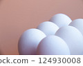 White Eggs arranged against Soft Pink backdrop, creating minimalist and modern aesthetic. Smooth, round shapes and pastel tones offer serene visual appeal, ideal photo for contemporary design themes 124930008