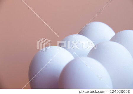 White Eggs arranged against Soft Pink backdrop, creating minimalist and modern aesthetic. Smooth, round shapes and pastel tones offer serene visual appeal, ideal photo for contemporary design themes 124930008