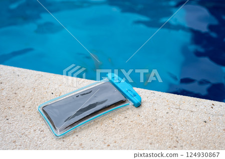 Waterproof case with a smartphone on the background of the pool on a sunny summer day Waterproof case with a smartphone on the background of the pool on a sunny summer day 124930867
