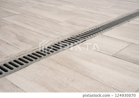 Water drain metal grate on light tiles close-up. Water drain metal grate on light tiles close-up. 124930870