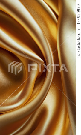 Luxurious golden satin fabric displaying intricate textures and smooth surface under subtle light 124930959