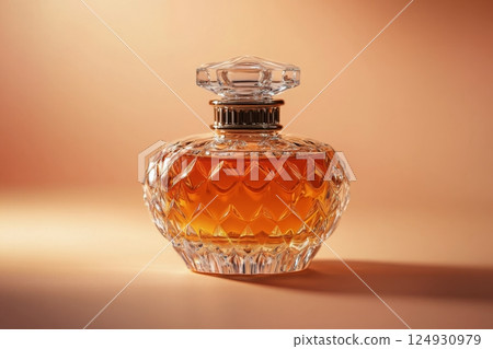 Elegant glass fragrance bottle with warm orange liquid on a textured orange background Elegant glass fragrance bottle with warm orange liquid on a textured orange background 124930979