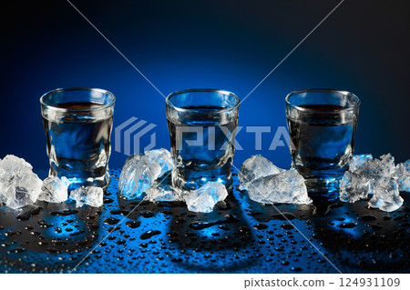 Vodka shots and and crushed ice on a black table. Vodka shots and and crushed ice on a black table. 124931109