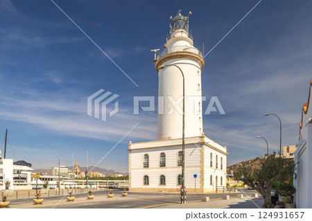 Malaga, seaside city in Andalusia, Spain, Europe. Coastal lighthouse on a sunny day, stands tall against a clear blue sky. A picturesque location. 124931657