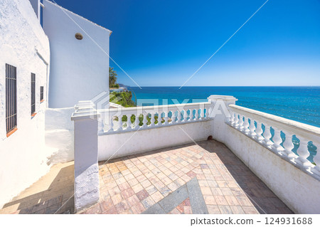 Nerja town, a resort of The Costa del Sol seaside region in Andalusia in the south of Spain. Mediterranean view from a white balcony. Ocean, blue sky, and tranquil scene. 124931688