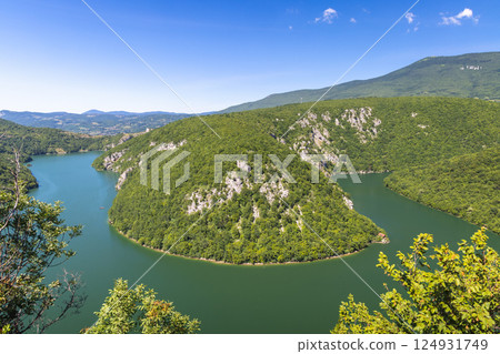 Canyon on the Vrbas River in Bosnia and Herzegovina, Europe. Verdant river valley with lush green forests and steep rocky cliffs under a clear blue sky. Serene nature scene from an elevated viewpoint. 124931749