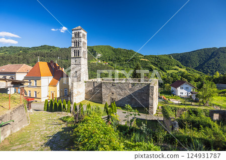 Jajce town in Bosnia and Herzegovina, Europe. Church of St. Mary with the tower of St. Luke. Historic stone tower and walls stand tall against a backdrop of lush green hills under a bright blue sky. 124931787