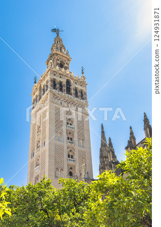 The Giralda bell tower of The Seville Cathedral, The Cathedral of Saint Mary of the See in Seville town, Andalusia, Spain, Europe. Tall, ornate tower against a bright blue sky. The Giralda bell tower of The Seville Cathedral, The Cathedral of Saint Mary of the See in Seville town, Andalusia, Spain, Europe. Tall, ornate tower against a bright blue sky. 124931871