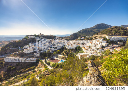 Casares town in Andalusia, Spain, Europe. White-washed village nestled in a mountain valley, bathed in sunlight. A picturesque scene of traditional architecture and stunning landscape. 124931895