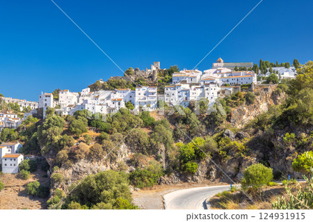 Casares town in Andalusia, Spain, Europe. Whitewashed village perched on a hillside, overlooking a winding road. Sunny day, stunning views. Casares town in Andalusia, Spain, Europe. Whitewashed village perched on a hillside, overlooking a winding road. Sunny day, stunning views. 124931915