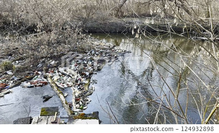 Dirty river is polluted with many plastic bottles. A lot of trash is dumped in open and freely available places at nature. Global environmental pollution problem. Concept of ecological disaster Dirty river is polluted with many plastic bottles. A lot of trash is dumped in open and freely available places at nature. Global environmental pollution problem. Concept of ecological disaster 124932898