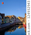 A European townscape with half-timbered houses along a canal and a hot air balloon 124932943
