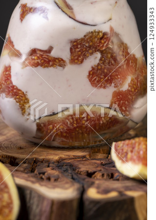 fresh pink yogurt with fig flavor in a glass jar and with red figs cut into pieces 124933343